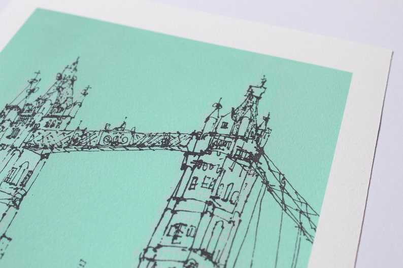 May include: A black and white line drawing of the Tower Bridge in London, against a light turquoise background.