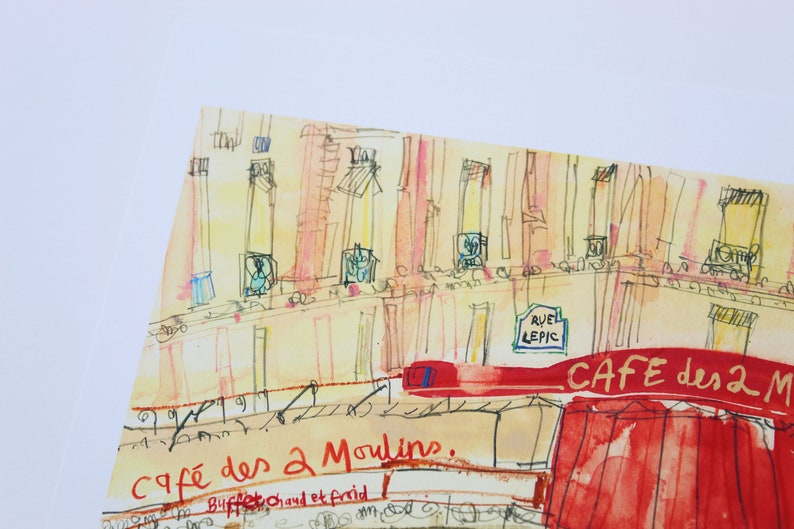 May include: Watercolor illustration of a Parisian cafe, "Cafe des 2 Moulins," with red awning and street sign. The artwork features a building facade with windows and the text "RUE LEPIC."