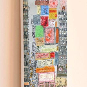 May include: A colorful illustration of a city street scene with tall buildings and many signs. The signs include the names of businesses like Dunkin Donuts, Hershey's, and Planet Hollywood. There are also many yellow taxis and people walking on the street.