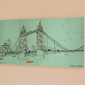 May include: A black and white line drawing of the Tower Bridge in London, England. The bridge is depicted against a light green background with a flock of birds flying overhead. The text "TOWER BRIDGE" is printed in black at the bottom right corner of the image.