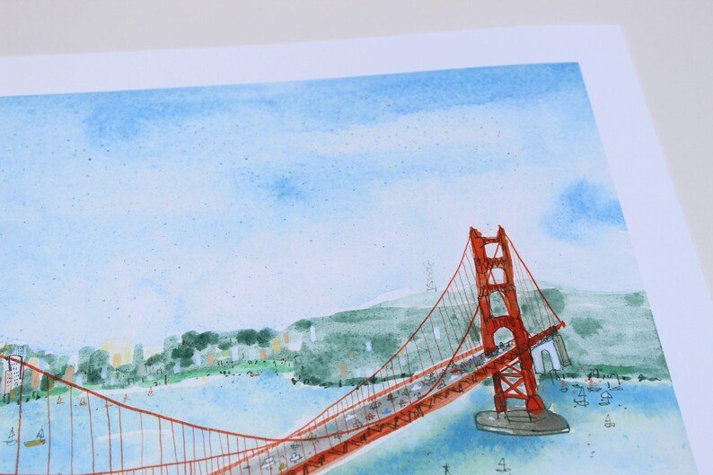 May include: A watercolor illustration of the Golden Gate Bridge in San Francisco, featuring a vibrant red suspension bridge spanning across blue water with green hills in the background and a light blue sky with soft, painted clouds above.
