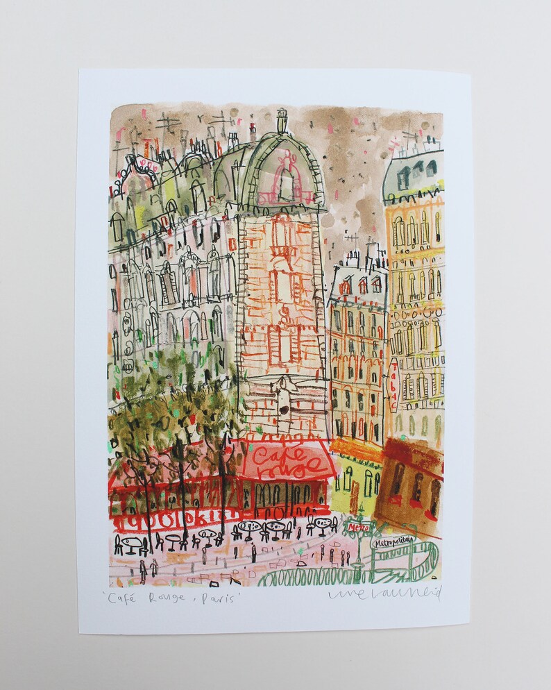 May include: A watercolor illustration of a Parisian cafe scene with a red building and a cafe called "Cafe Rouge" with tables and chairs outside. The text "Cafe Rouge, Paris" and "line launeid" are written at the bottom of the image.