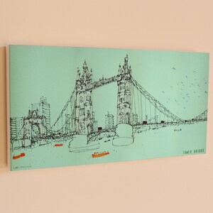 May include: A black and white line drawing of Tower Bridge in London, England. The bridge is drawn on a light blue background with small boats and birds in the sky. The text "TOWER BRIDGE" is in the bottom right corner.