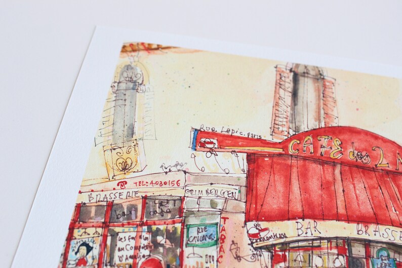 May include: Watercolor painting of a Parisian cafe, featuring a red awning with the words "CAFE des 2 Moulins". The artwork includes architectural details, street signs, and the text "Rue Lepic. paris". The style is loose and impressionistic.