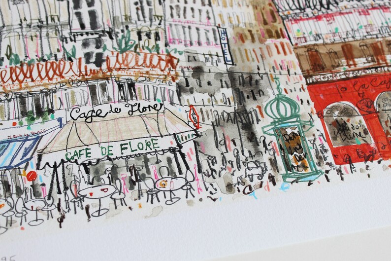 May include: A watercolor illustration of a Parisian street scene with a cafe called "Cafe de Flore" and a red building with the text "To La Cafe" in French. The illustration is done in a loose, sketchy style with black ink and watercolor washes.