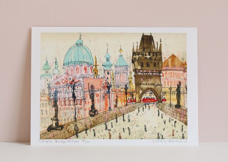 May include: A watercolor painting of Charles Bridge in Prague, Czech Republic. The painting features a view of the bridge with the iconic towers and the Vltava River in the background. The painting is done in a loose, expressive style with a mix of colors, including pink, blue, green, and brown.