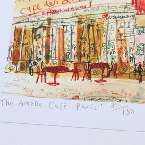May include: Watercolor print of a Parisian cafe scene, featuring red tables and chairs, and the text "The Amelie Caf&eacute; Paris". The artwork depicts a bustling street scene with storefronts and figures.