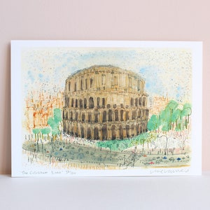 May include: Watercolor print of the Colosseum in Rome. The artwork depicts the ancient amphitheater in shades of brown and beige, with green trees and a light blue sky. The print includes the text "The Colosseum Rome" and is signed.