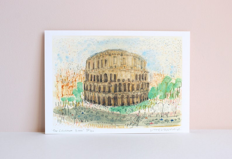 May include: Watercolor print of the Colosseum in Rome. The artwork depicts the ancient amphitheater in shades of brown and beige, with green trees and a light blue sky. The print includes the text "The Colosseum Rome" and is signed.