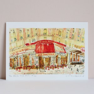 May include: Watercolor print of the "Cafe des 2 Moulins" in Paris, featuring a red awning and the words "Bar Brasserie." The artwork depicts a street scene with tables and figures, and the text "The Amelie Cafe Paris" is visible.