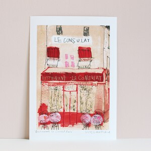 May include: A hand-drawn illustration of a Parisian cafe called "Le Consulat" with red awnings and a red sign that says "Restaurant - Le Consulat". The cafe has a cafe sign and a few tables with chairs outside.