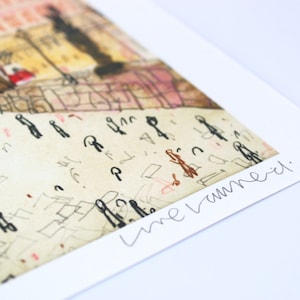 May include: A close-up of a signed art print with a whimsical illustration of a city scene. The signature reads "Lune Vermeil."