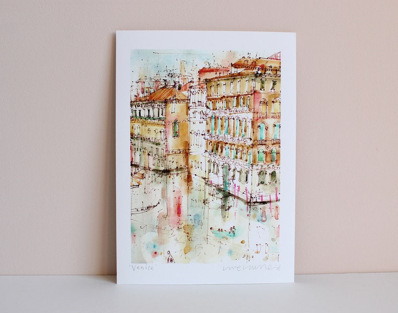 May include: Watercolour painting of buildings in Venice, Italy. The buildings are painted in shades of yellow, orange, and red. The water in the canal is a light blue colour. The painting is signed "Venice" in the bottom left corner and "Love Venice" in the bottom right corner.