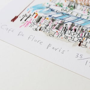 May include: A black and white sketch of a cafe in Paris, France. The cafe is called "Cafe De Flore" and the sketch is numbered 35/195.