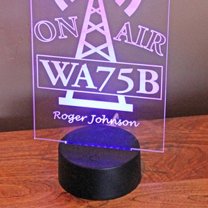 May include: A pink and white LED light with a radio tower design. The light has a remote control and says "ON AIR WA75B Roger Johnson".