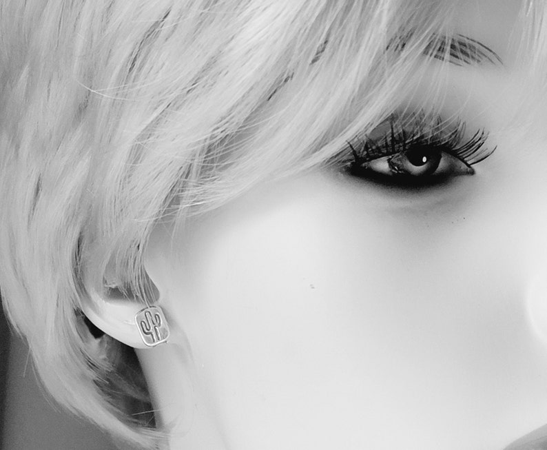 May include: A close-up of a woman's ear with a small silver cactus earring.