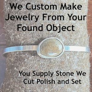 May include: A silver bracelet with a light brown stone set in a silver bezel. The text "We Custom Make Jewelry From Your Found Object You Supply Stone We Cut Polish and Set" is visible in the image.