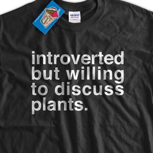 K&ouml;nnte beinhalten: Schwarzes T-Shirt mit wei&szlig;em Text, der "introvertiert, aber bereit, &uuml;ber Pflanzen zu diskutieren" lautet.