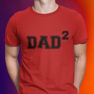 May include: Red t-shirt with black text that reads "DAD²" in a collegiate font.