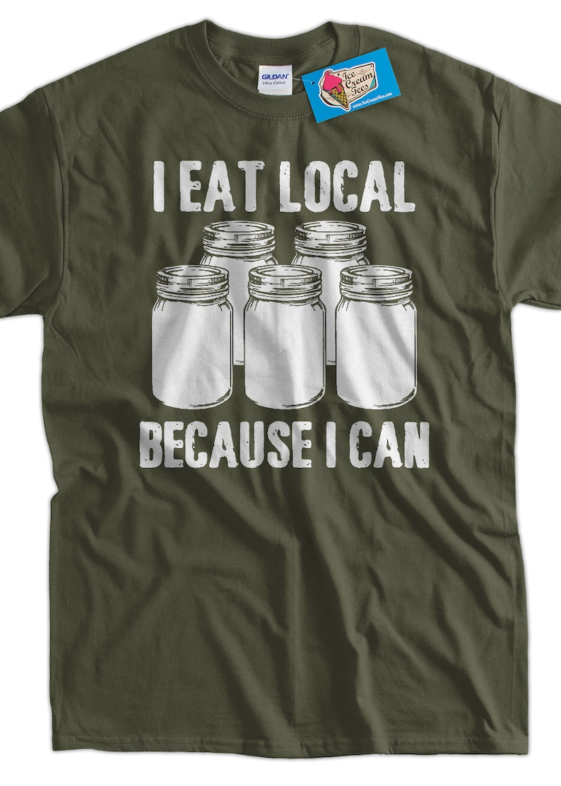 May include: A green t-shirt with white text that reads "I eat local because I can". The text is surrounded by five white mason jars.