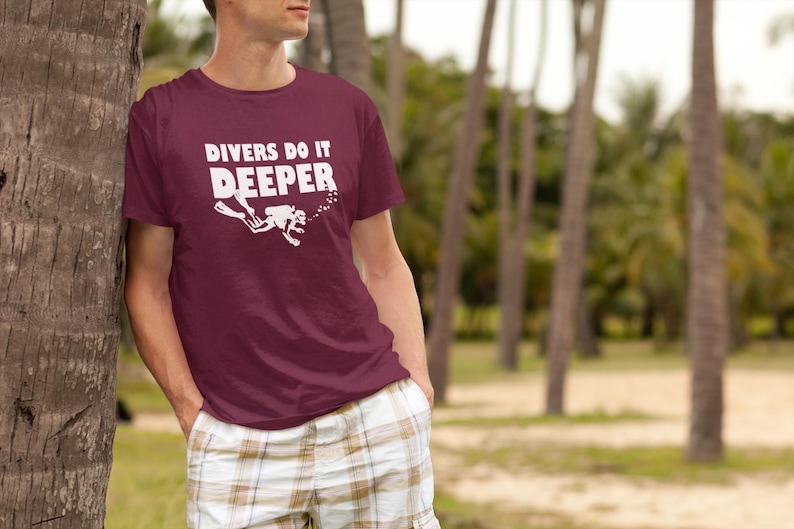 May include: A maroon t-shirt with a white graphic of a scuba diver and the text "Divers Do It Deeper".