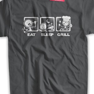 May include: A dark gray t-shirt with a white graphic of a stick figure eating, sleeping, and grilling. The text "Eat Sleep Grill" is below the graphic.