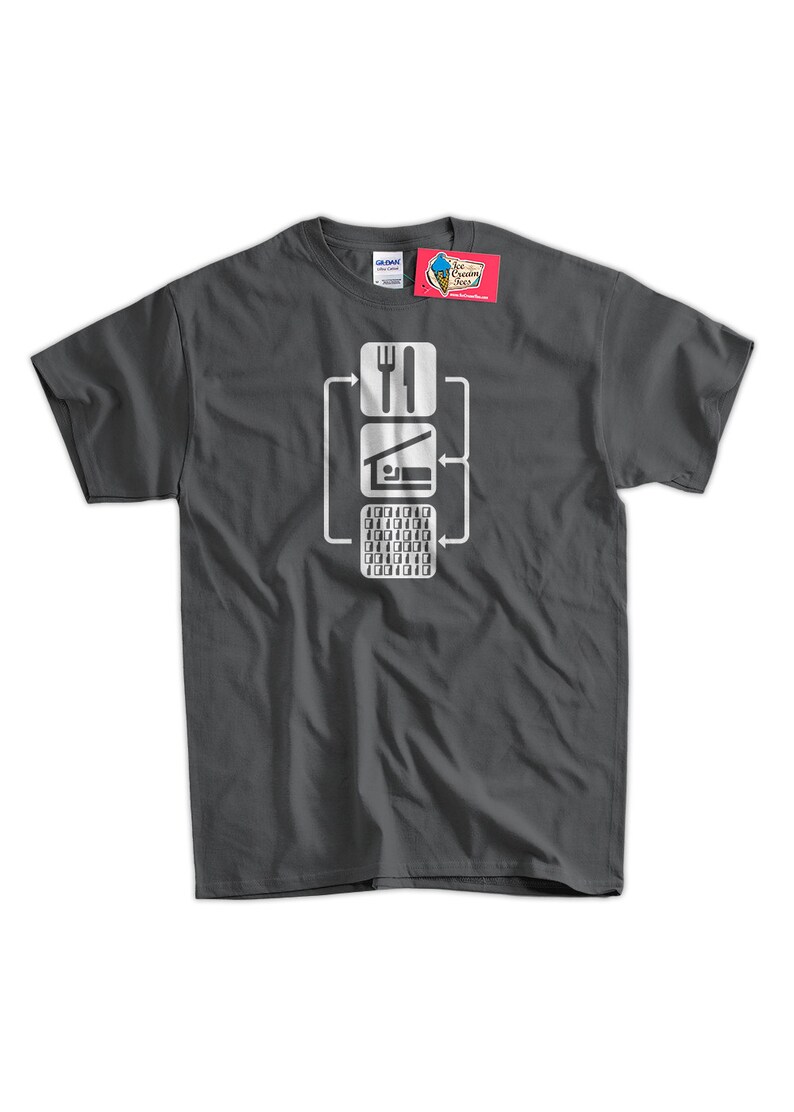 Peut inclure: Un t-shirt gris fonc&eacute; avec un graphique blanc repr&eacute;sentant un organigramme. L'organigramme montre une fourchette et un couteau, une maison avec un lit et un clavier d'ordinateur. Le texte sur le t-shirt est "Manger, Dormir, Coder, R&eacute;p&eacute;ter."