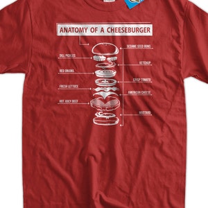 May include: Red t-shirt featuring a detailed diagram of a cheeseburger, labeled "Anatomy of a Cheeseburger." The diagram shows the layers: sesame seed buns, dill pickles, red onions, fresh lettuce, hot juicy beef, ketchup, crisp tomato, American cheese, and mustard.