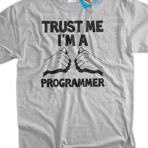May include: Grey t-shirt with the text "Trust me I'm a programmer" and two black fists with thumbs up.