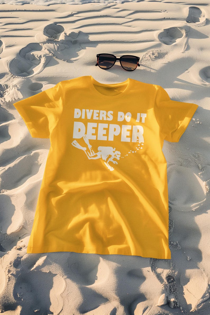May include: A yellow t-shirt with the text "Divers Do It Deeper" in white lettering. A white silhouette of a scuba diver is below the text.