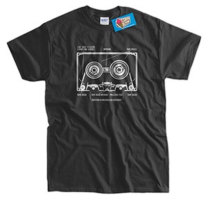 May include: A black t-shirt with a white graphic of a cassette tape. The graphic shows the different parts of the cassette tape, including the tape reels, window, tape head opening, pressure pad, and capstan & pinch roller openings.