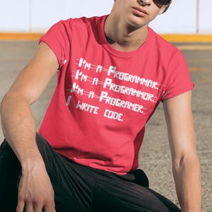 Peut inclure: Un t-shirt rouge avec du texte blanc qui dit "I'M A PROGRAMMAR. I'M A PROGRAMMOR. I'M A PROGRAMER. WRITE CODE."