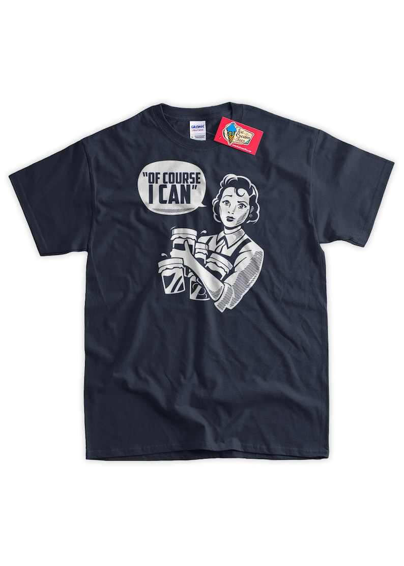 May include: A navy blue t-shirt with a white graphic of a woman holding multiple cups and a speech bubble that says "Of course I can".