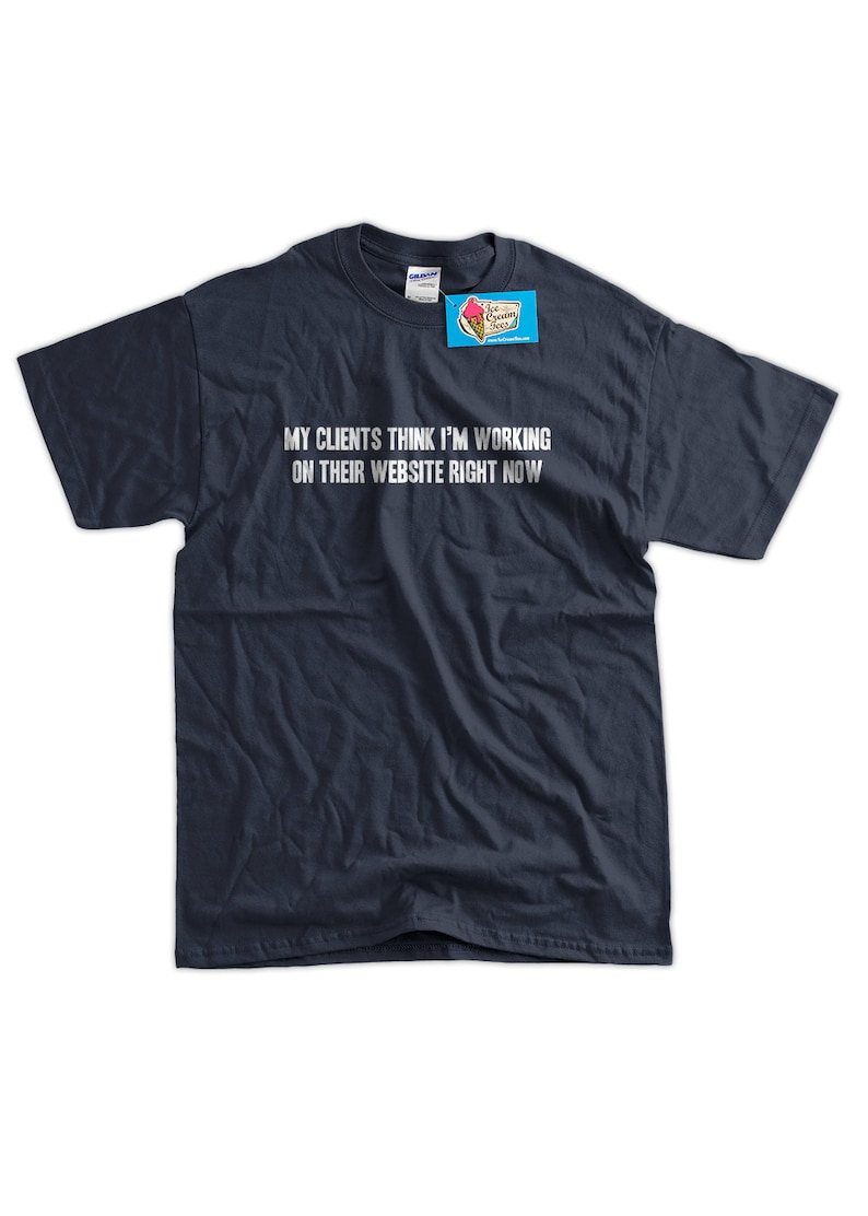 Puede incluir: Una camiseta azul marino con el texto "Mis clientes piensan que estoy trabajando en su sitio web ahora mismo" impreso en blanco.