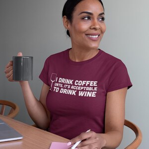 May include: A maroon t-shirt with a white graphic that reads "I drink coffee until it's acceptable to drink wine". The graphic includes a wine glass icon.