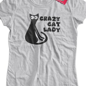 Może przedstawiać: Szara koszulka z ilustracją czarnego kota i tekstem "Crazy Cat Lady".