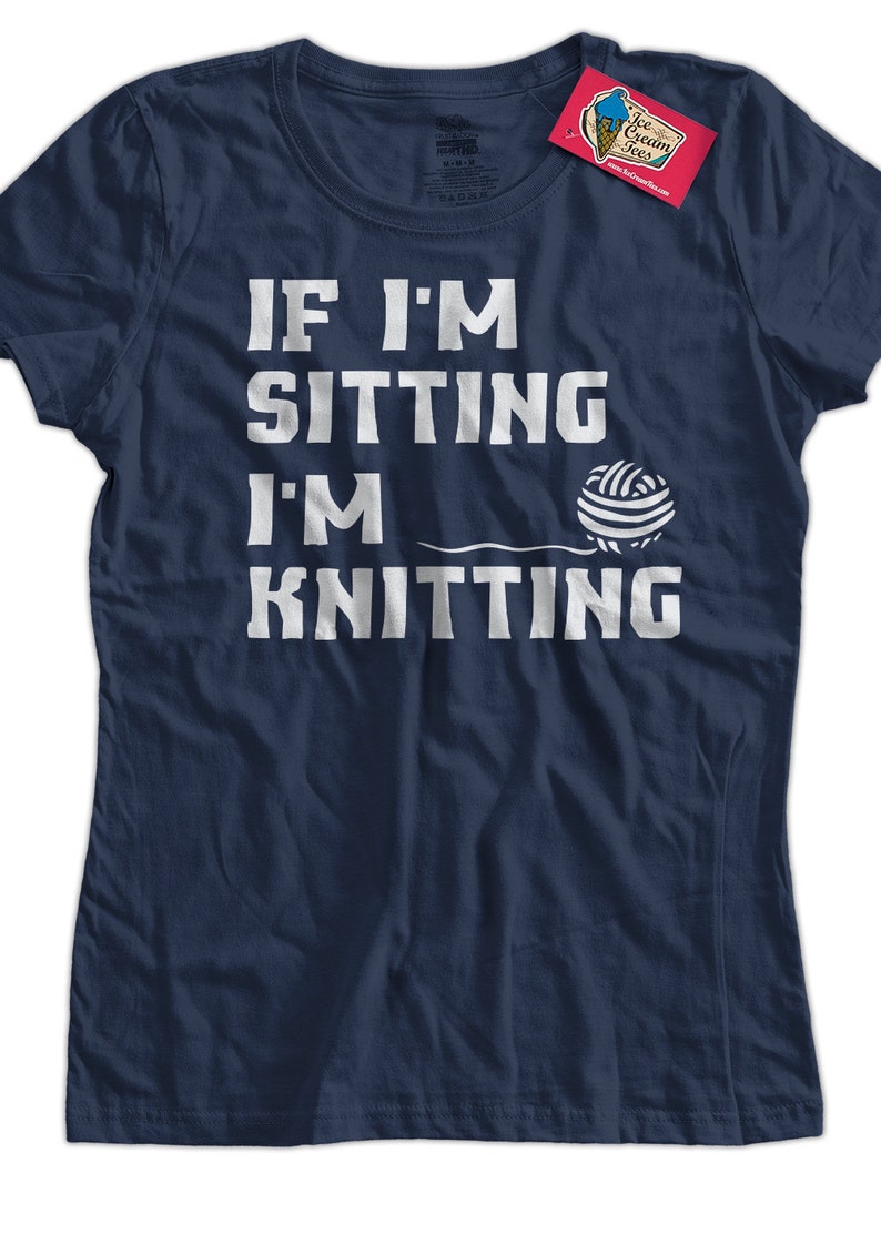 May include: A navy blue t-shirt with white text that reads "If I'm sitting I'm knitting" and a white illustration of a ball of yarn.