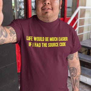 Peut inclure: Un t-shirt bordeaux avec le texte "Life would be much easier if I had the source code" imprimé en jaune.