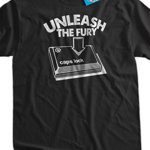 May include: Black t-shirt with white text that reads "UNLEASH THE FURY" with an arrow pointing down to a white illustration of a keyboard key labeled "caps lock".