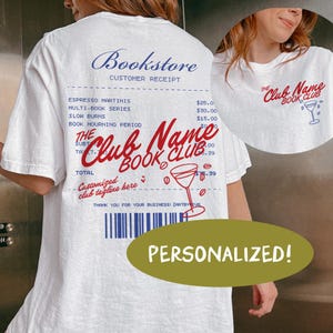 Op de afbeelding: Wit T-shirt met een ontwerp van een boekhandelaarsbon, met de tekst "Bookstore" en "The Club Name Book Club". Het ontwerp bevat een cocktailglas illustratie en het woord "PERSONALIZED!" in een groene ovaal.