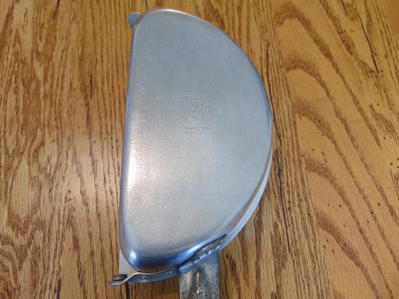 Puede incluir: Un plato de metal plateado en forma de semic&iacute;rculo con un asa. El plato tiene un logotipo que dice "Universal" y "Trade Mark" con "Made in U.S.A." debajo.