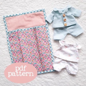 May include: A PDF pattern for a doll's sleeping bag and two sets of pajamas. The sleeping bag is pink and white with a floral print. The pajamas are blue and white with a floral print. The text "pdf pattern" is written in a circle on the image.
