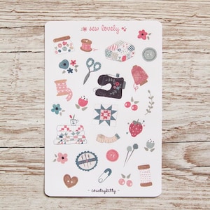 May include: A sheet of stickers featuring a variety of sewing-themed illustrations, including a sewing machine, spools of thread, buttons, needles, and fabric scraps. The stickers are on a white background and have a pink and blue color scheme. The text "sew lovely" is at the top of the sheet, and the text "countrykitty" is at the bottom.