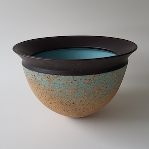 May include: A ceramic bowl with a brown rim and a speckled glaze in shades of blue and orange.