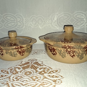 May include: Two ceramic casserole dishes with lids. The dishes are brown with a speckled glaze in shades of brown, green, and white.