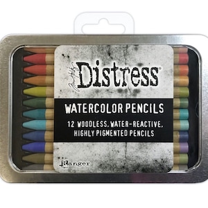 May include: A metal tin containing 12 woodless, water-reactive, highly pigmented watercolor pencils. The pencils are arranged in a row and are labeled "Distress Watercolor Pencils" and "Ranger".