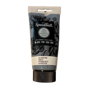 May include: A tube of Speedball block printing ink in Bluestone color. The tube is gray with black floral illustrations and text. The ink is water-soluble and suitable for linoleum block printing.