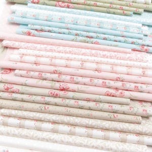 May include: A stack of fabric pieces in various pastel colors, including pink, blue, and green. The fabrics feature floral and patterned designs, with rolled edges. The fabrics are suitable for quilting, sewing, and other craft projects.