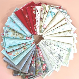 May include: A circular arrangement of folded fabric squares in various floral and patterned designs. Colors include red, light blue, gray, and cream. Some fabrics feature script text. Ideal for quilting or crafting projects.