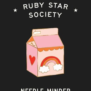 May include: A pink milk carton with a gold outline and a rainbow, heart, and clouds design. The text "RUBY STAR SOCIETY" and "NEEDLE MINDER by Melody Miller" is printed below the carton.